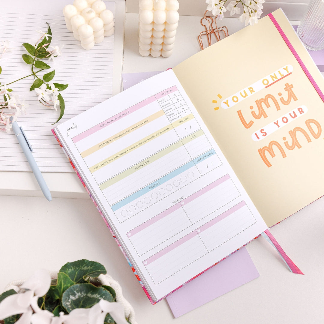 2025 Teacher Planner open to the goal-setting page, featuring neatly structured sections for personal and professional goals, surrounded by colourful design props like pens and floral accents.