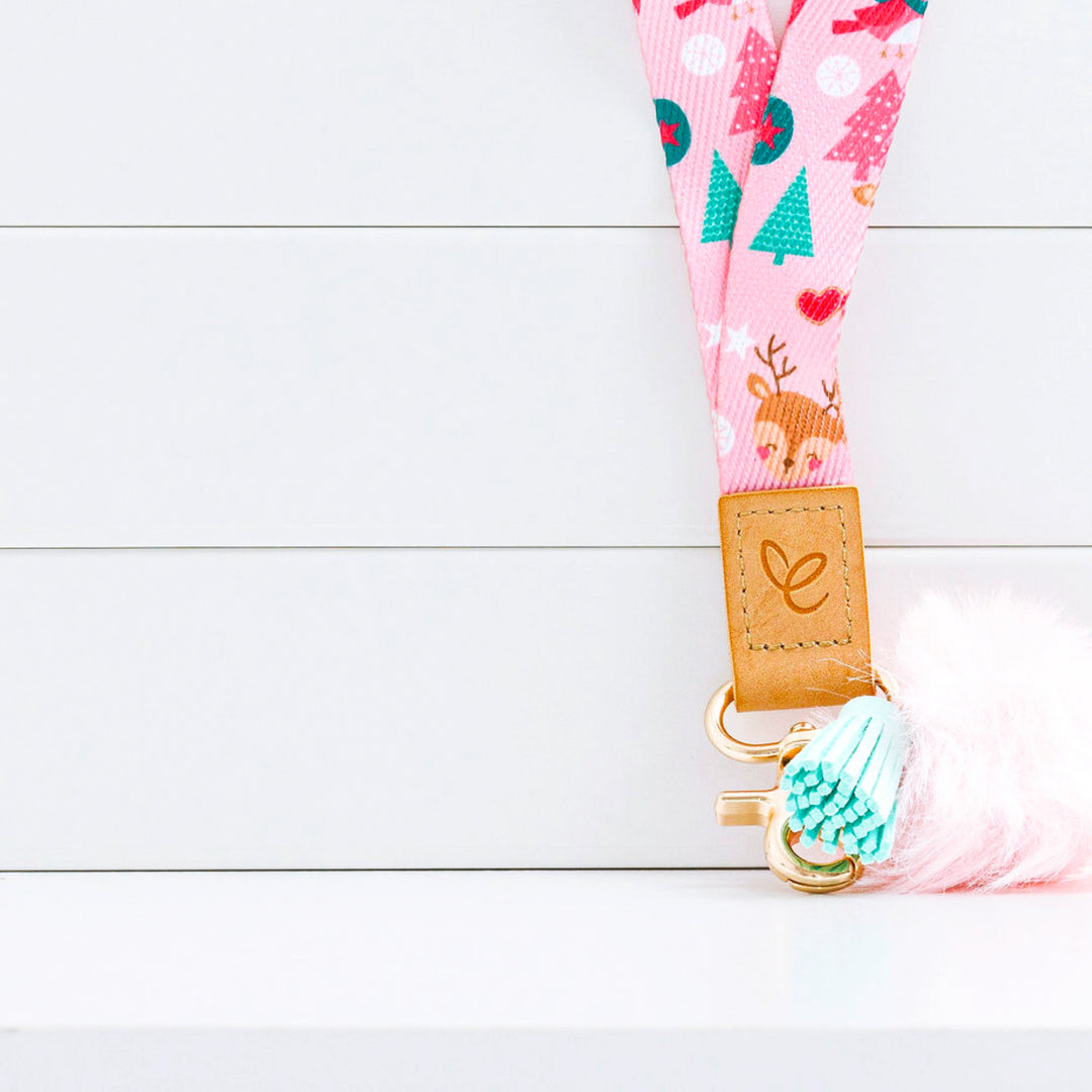 Close-up of pastel pink Christmas lanyard with festive prints, pom-pom, aqua tassel, gold clasp, and 'Mrs Edgar' patch.