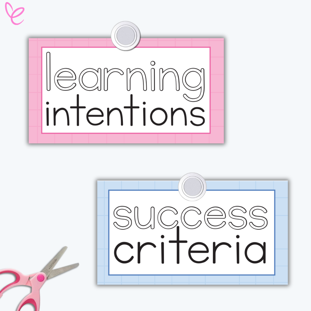 Two learning display signs for 'Learning Intentions' and 'Success Criteria' on pink and blue backgrounds. A pair of pink-handled scissors in the corner suggests a DIY classroom resource.