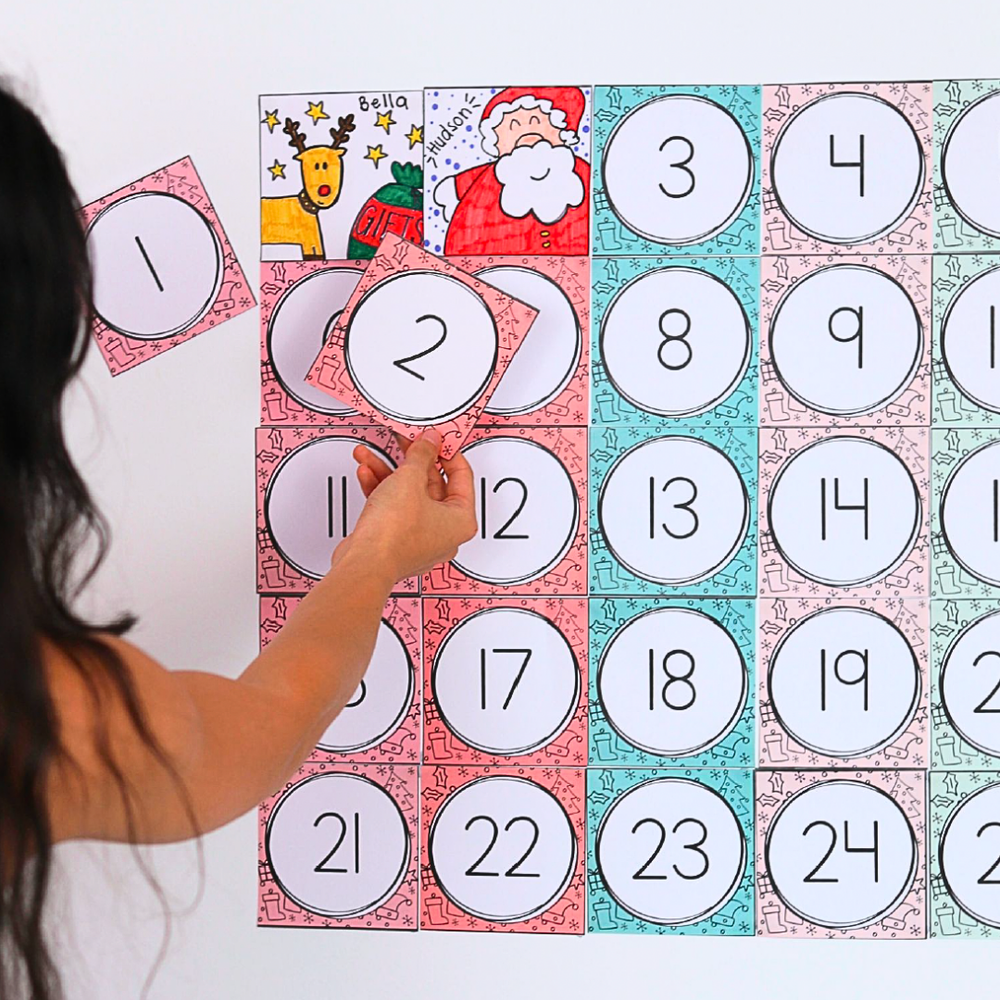 Completed digital Christmas Advent Calendar placed on a white wall with a person holding number 1 and 2.