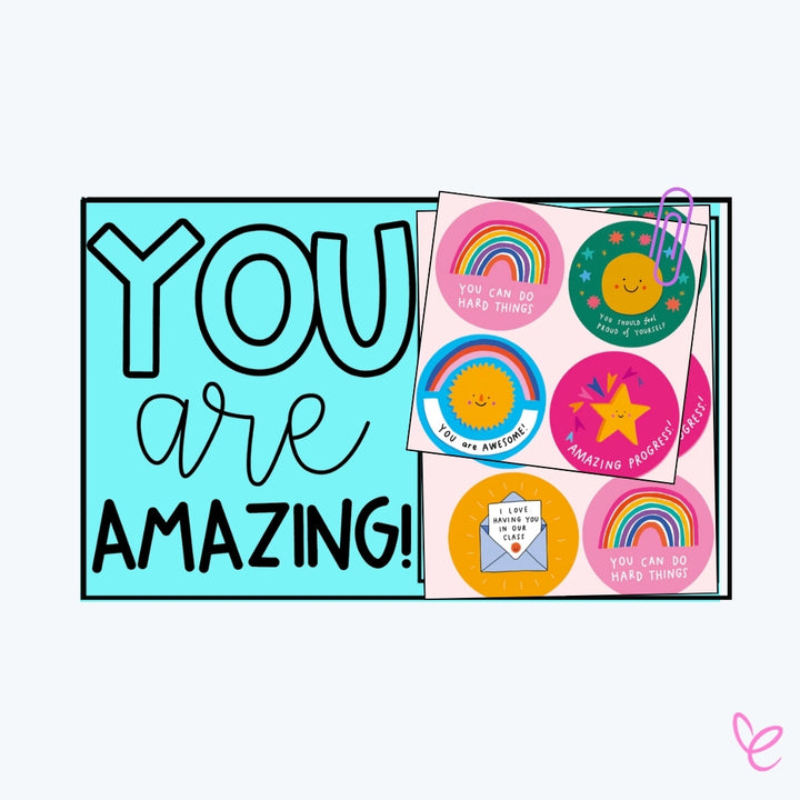  A light blue classroom sign with bold text stating, "YOU are AMAZING!" A sheet of round motivational stickers featuring rainbows, stars, and encouraging messages like "You can do hard things" is clipped to the sign.