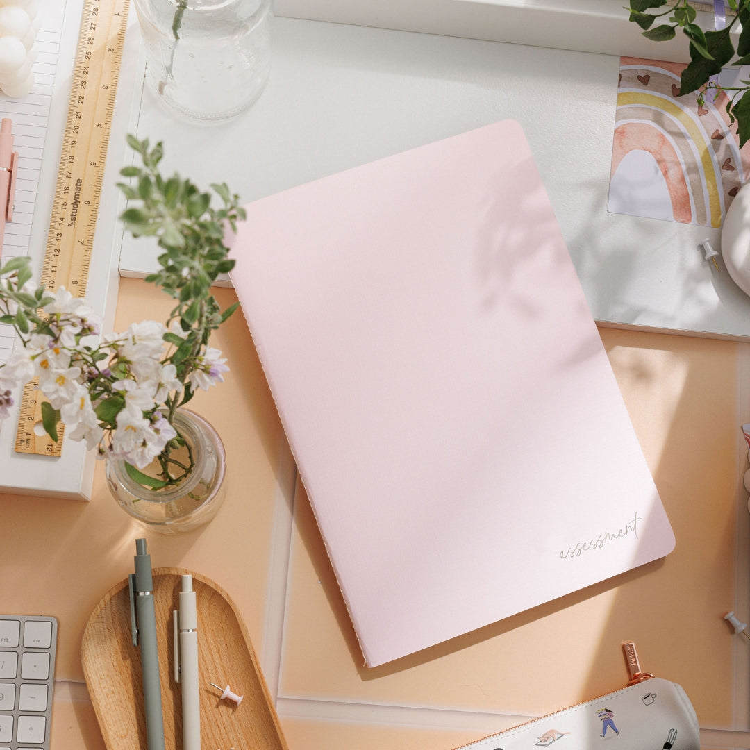 Blush assessment journal laid flat on a decorative table, showcasing its elegant design against a stylish backdrop.