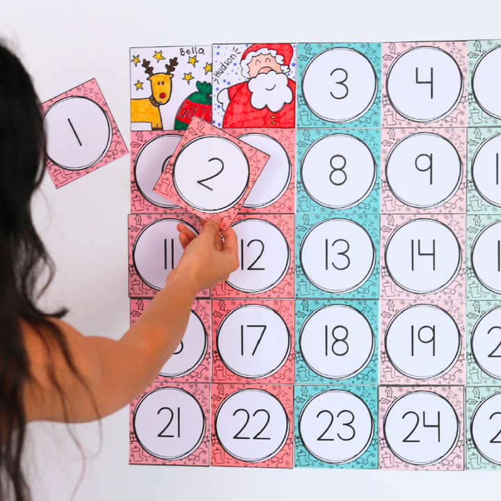 Person removing two Christmas Advent Calendar cards, revealing a drawing behind each of them.