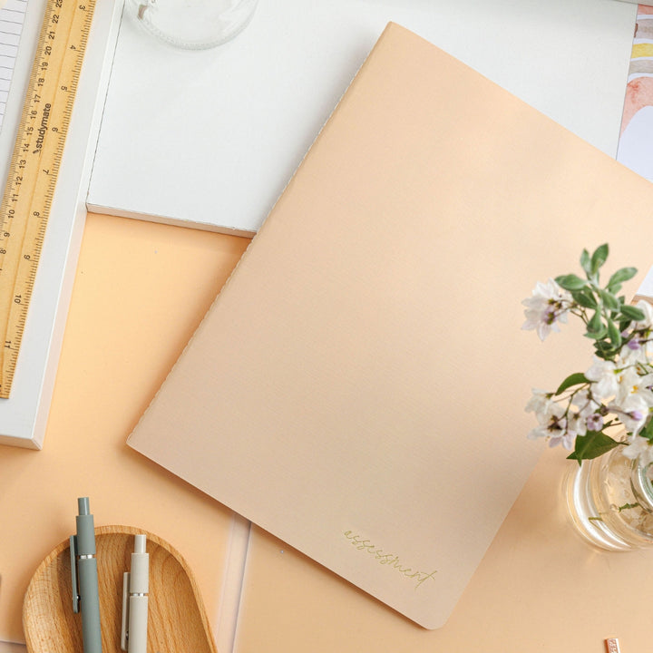 Flat-lay of the tan assessment journal on a decorative table, emphasising its elegant design against a sophisticated background.