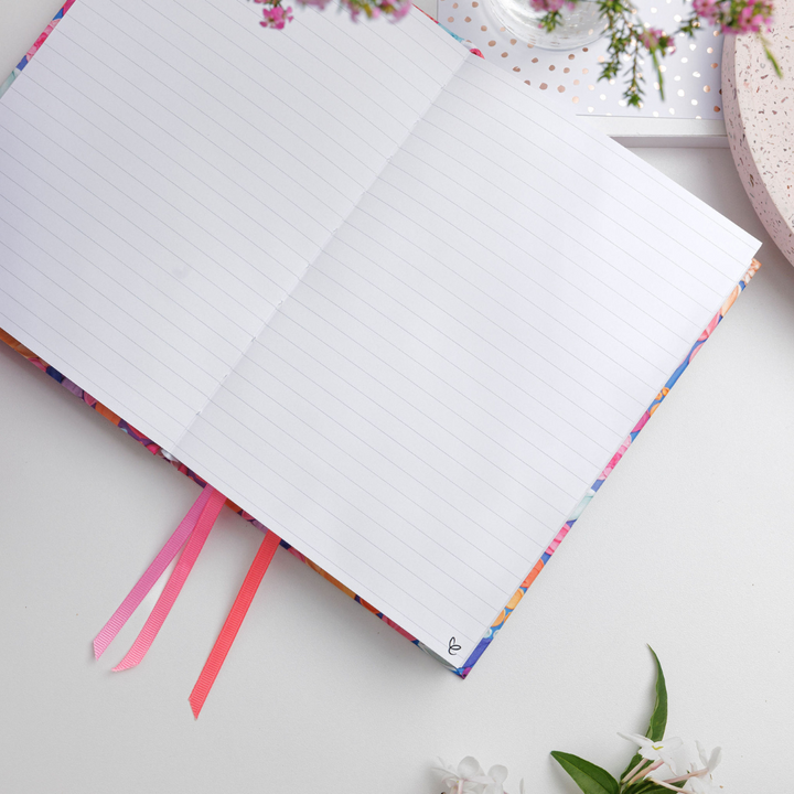 Awakening A5 Notepad lying open on a desk, displaying lined pages with ample space for writing notes or lists