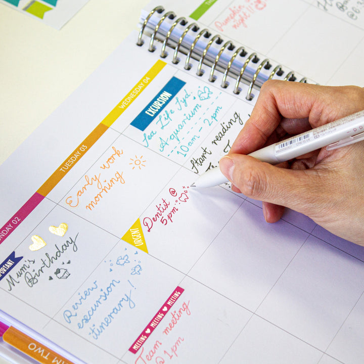 Teacher writing in planner using a red Waai ballpoint pen with erasable ink, detailing lesson plans and notes